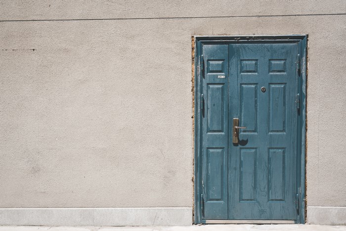 Blue double door set into a stucco wall