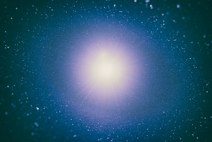 A bright light emanates from a starry galaxy