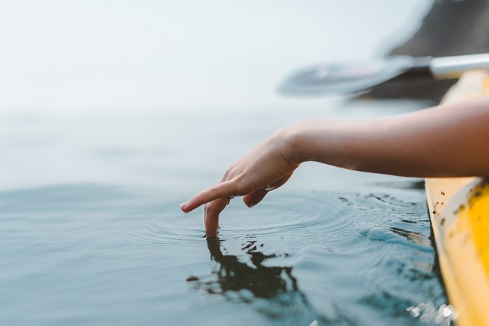 Hand dipping finger in water from a kayak