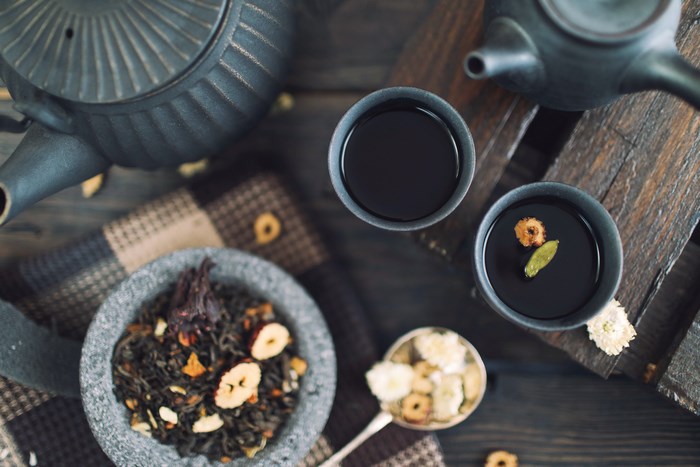 Tea ceremony with teapot, cups, and dried ingredients