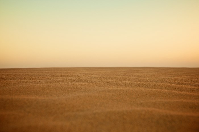 Sand dunes under a golden sky at sunrise or sunset