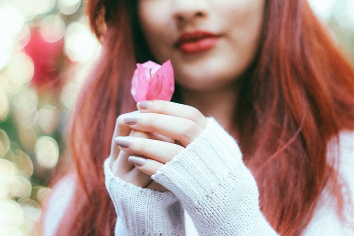 Woman with red hair holding a pink flower
