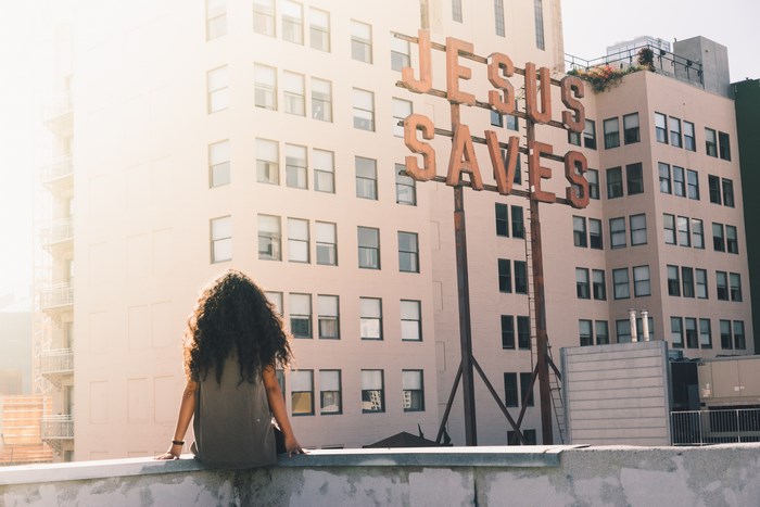 Woman on a rooftop with Jesus Saves sign