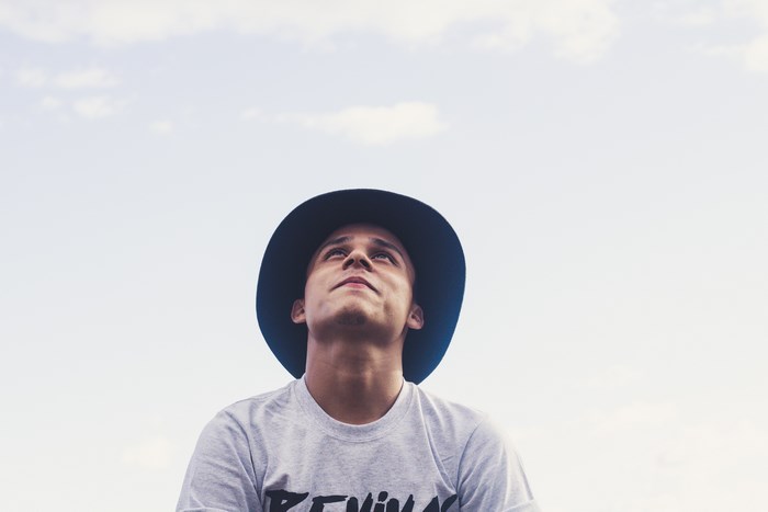 Man wearing a hat and t-shirt looking up at the sky