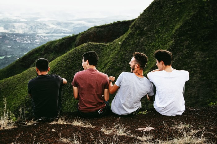 Four young men sitting on a mountain edge