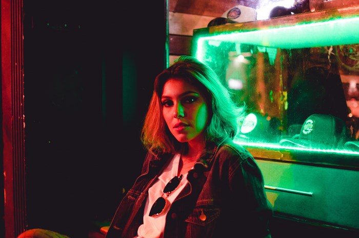Woman in a denim jacket under green and red lights
