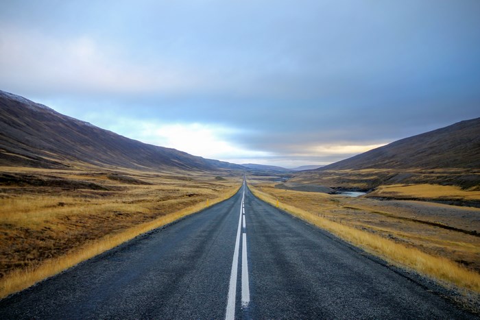 Straight asphalt road through a cloudy mountain landscape