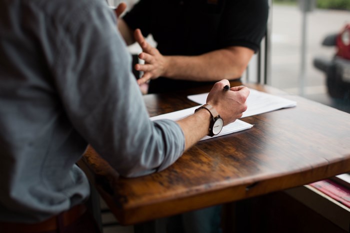 Two men in a meeting discussing papers at a table