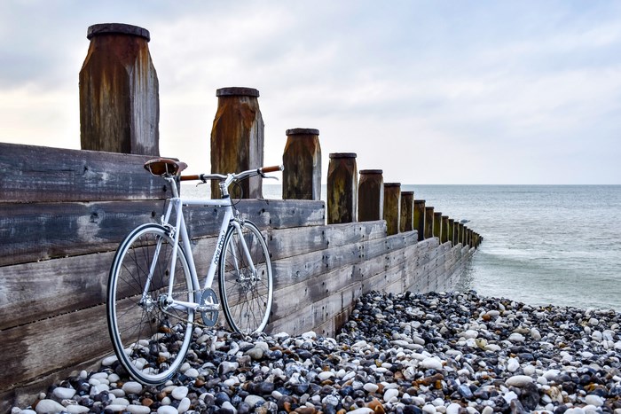 White bicycle on a pebble beach with wooden sea defense