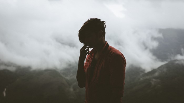Man in red shirt thinking in foggy mountains