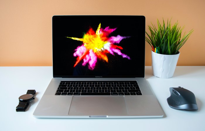 MacBook Pro with colorful explosion wallpaper on desk