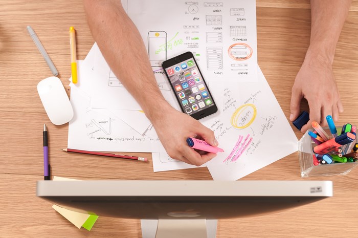 Person working on design with iPhone and iMac