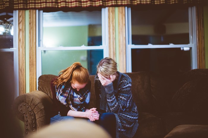 Two women praying on a couch