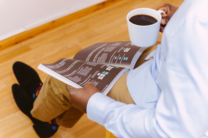Man reading a magazine and drinking coffee