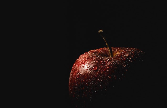 Red apple with water droplets on black background