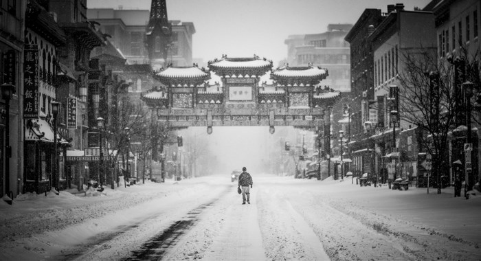 Chinatown gate in a snowstorm with a person walking