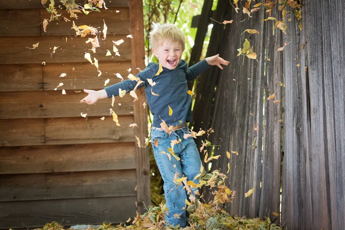 Happy boy throwing leaves in the fall