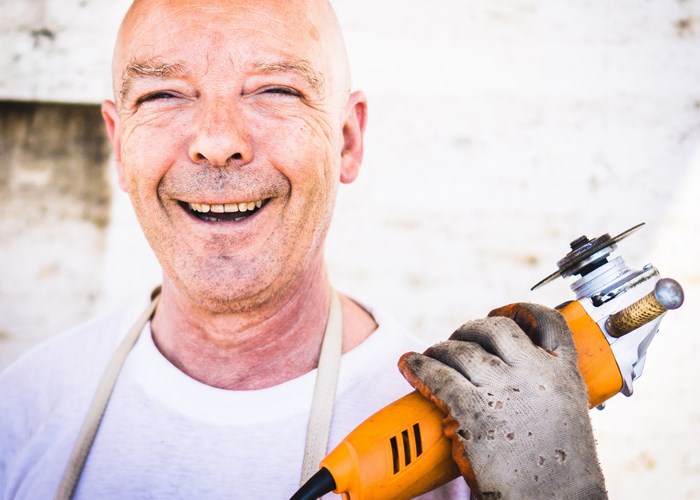 Bald man with a disc grinder and a smile
