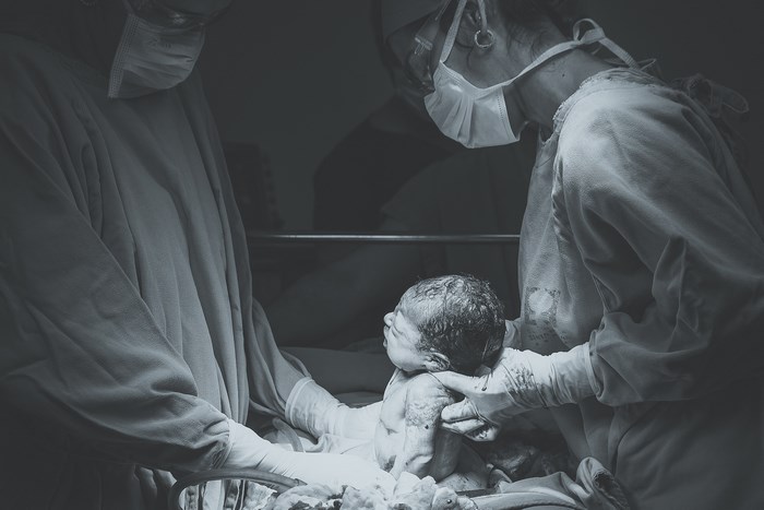 Surgeons deliver a newborn baby during a surgery