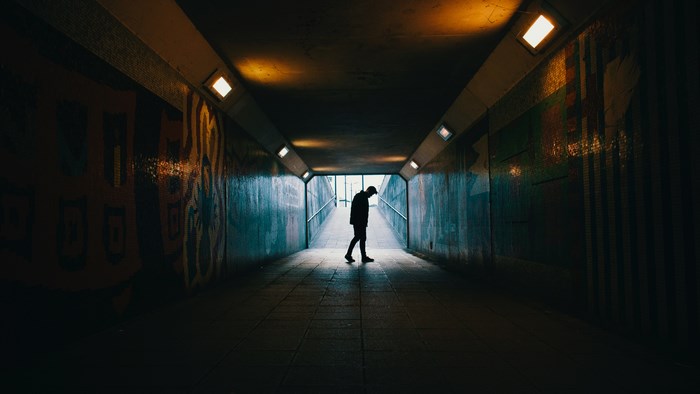 Silhouette of a Man Walking in a Dimly Lit Tunnel