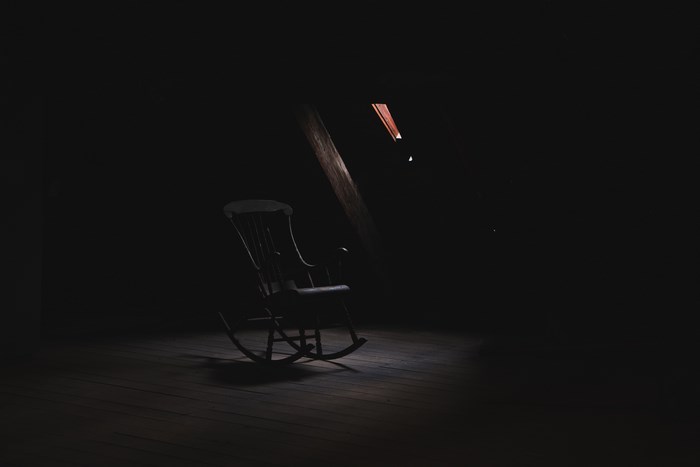 A dark attic with a rocking chair in the light