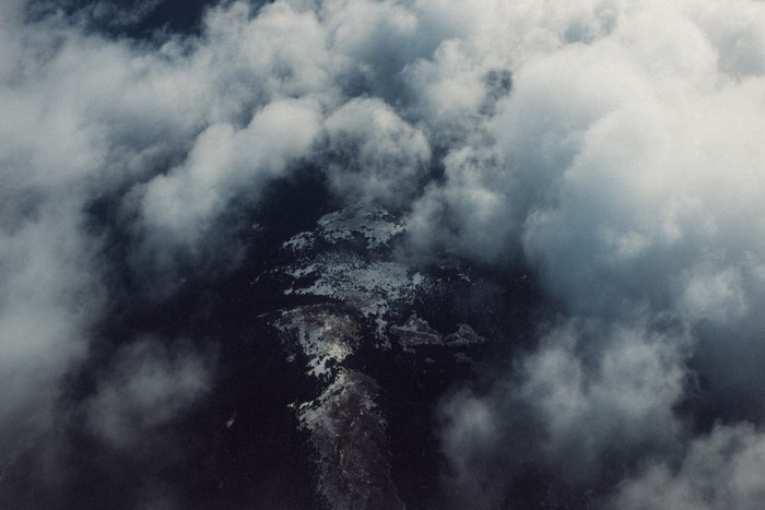 Aerial view of a snow-covered mountain through clouds