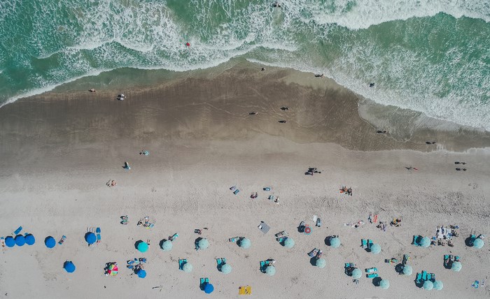 Aerial view of a crowded beach with teal umbrellas