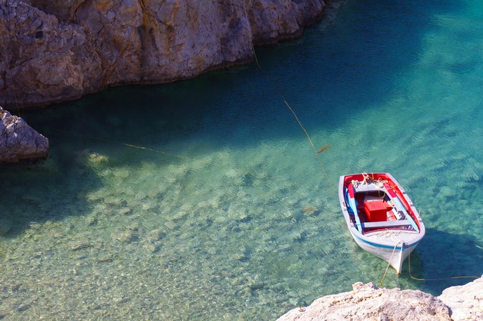 A small boat is docked in a clear turquoise cove.