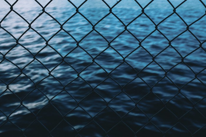 Chain link fence in front of blue ocean water
