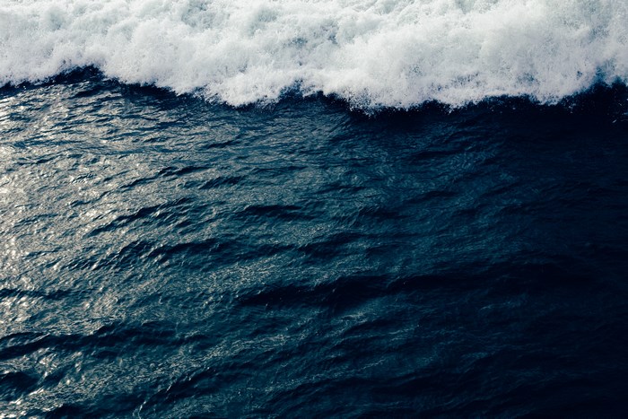 Ocean wave crashing with white foam and dark blue water