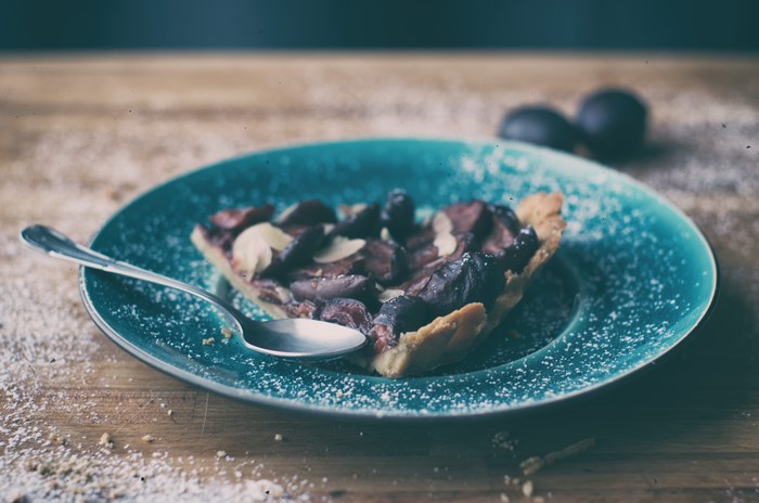 Slice of plum tart with almonds on a plate