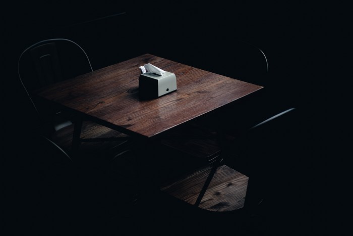 Dimly Lit Wooden Table with Chairs and Napkin Holder