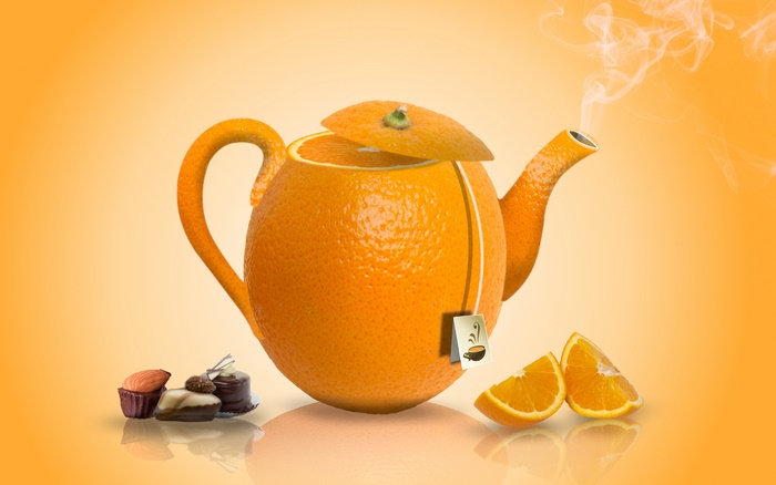 Orange teapot with tea bag and chocolates
