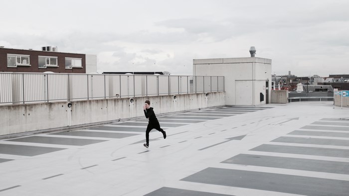 A person running on a concrete rooftop parking lot