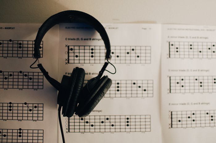 Headphones hanging over guitar chord charts