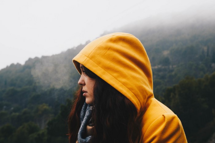 Woman in yellow hood on misty mountain