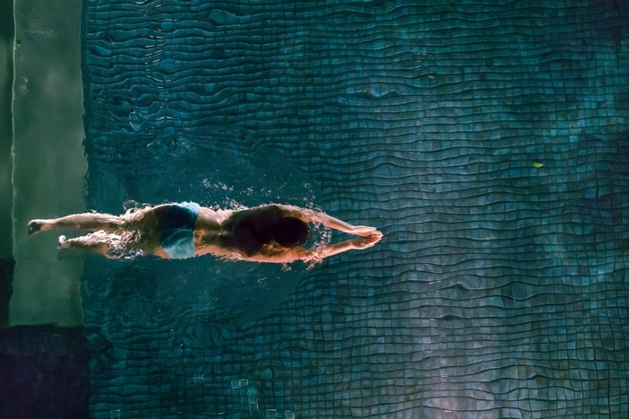 Woman swimming in a luxury swimming pool at night