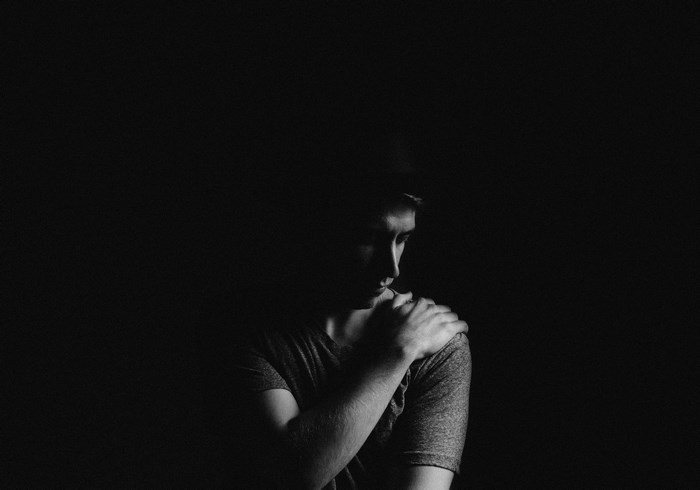 Man with hand on shoulder in shadow