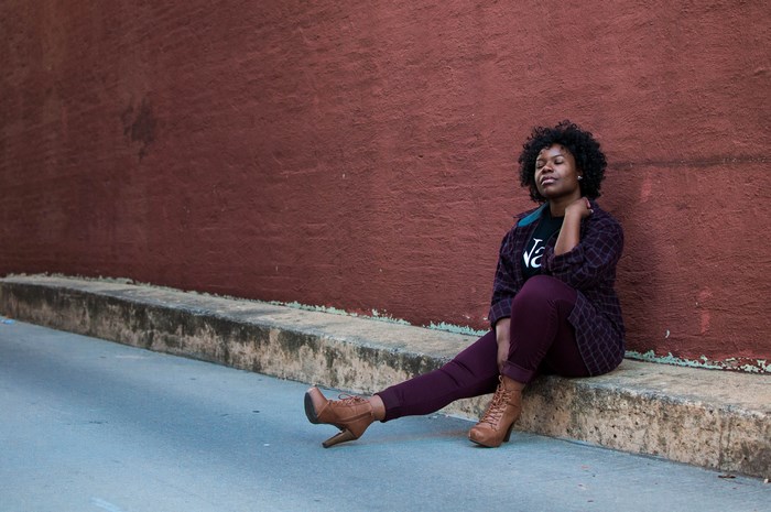 Woman with curly hair sitting by a wall