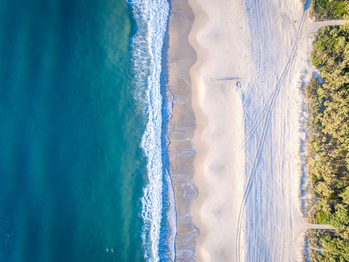Aerial view of a sandy beach with turquoise ocean waves