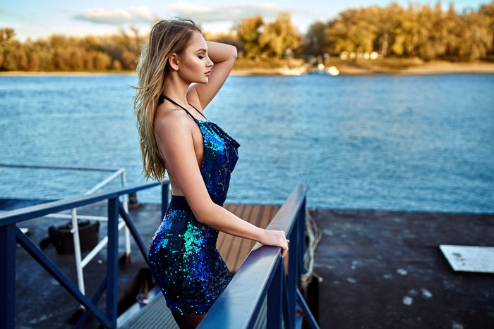 Woman in blue sequin dress by the water