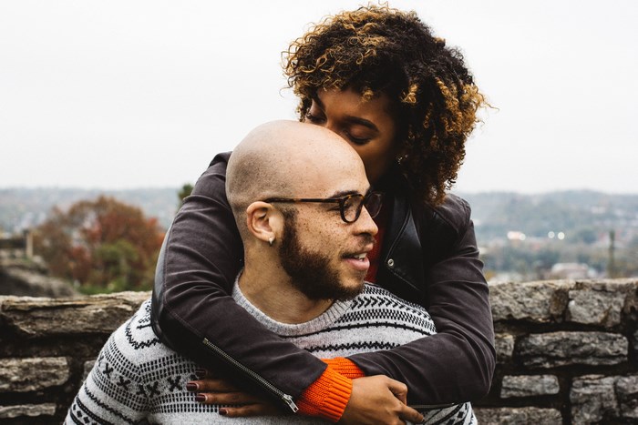 Couple embracing outdoors with a stone wall