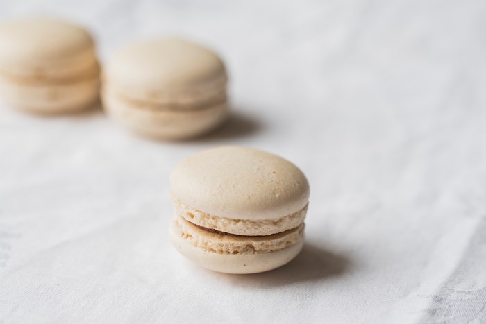 Three beige macarons on a white tablecloth