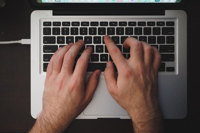 Man typing on a MacBook laptop