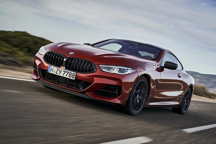 Red BMW 8 Series Coupe driving on a road