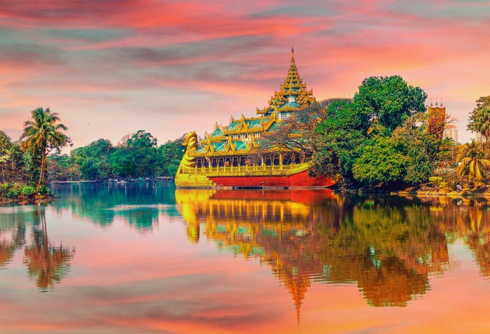 Golden Buddhist barge on a lake at sunset