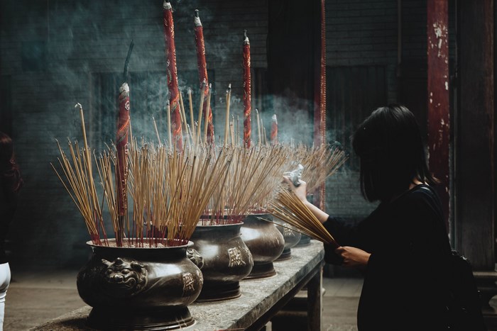Woman lighting incense sticks in a temple