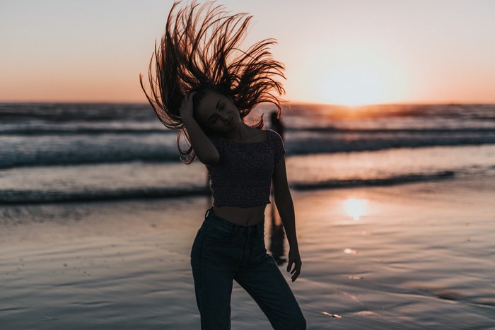 Woman Enjoying Sunset on Beach with Flowing Hair