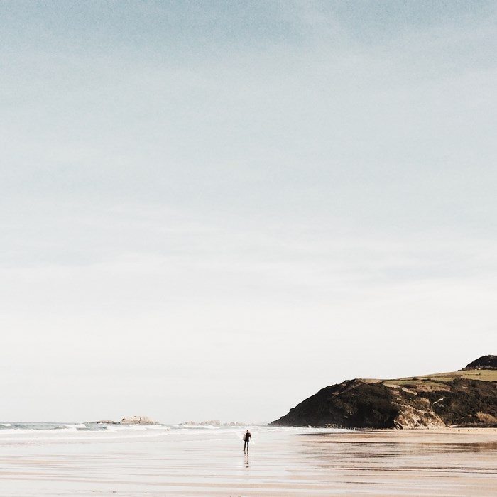 Man standing on a beach with a mountain in the background