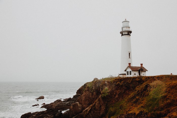 White lighthouse on a cliff overlooking the ocean